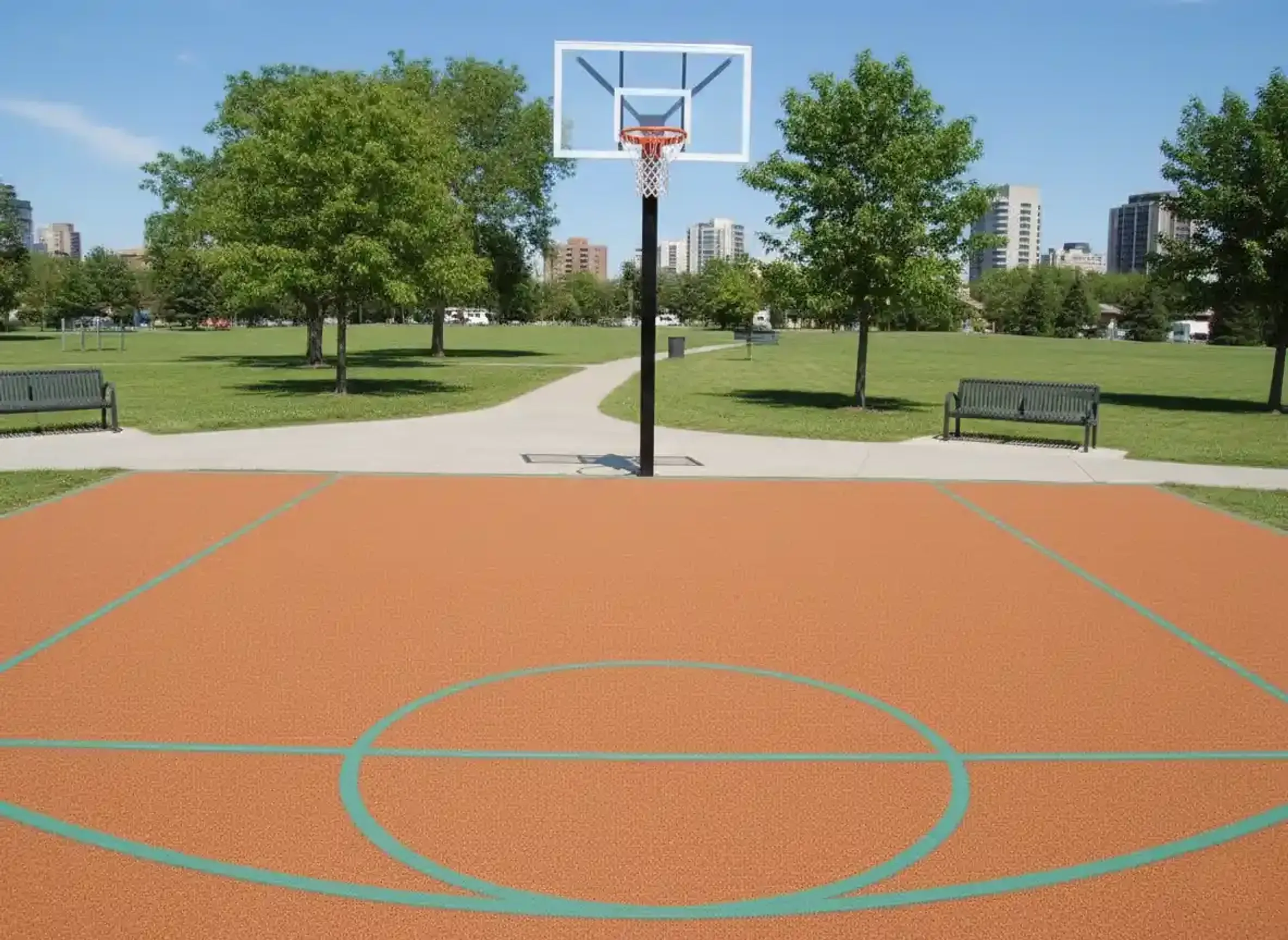 Outdoor basketball court with orange rubber surfacing and teal lines